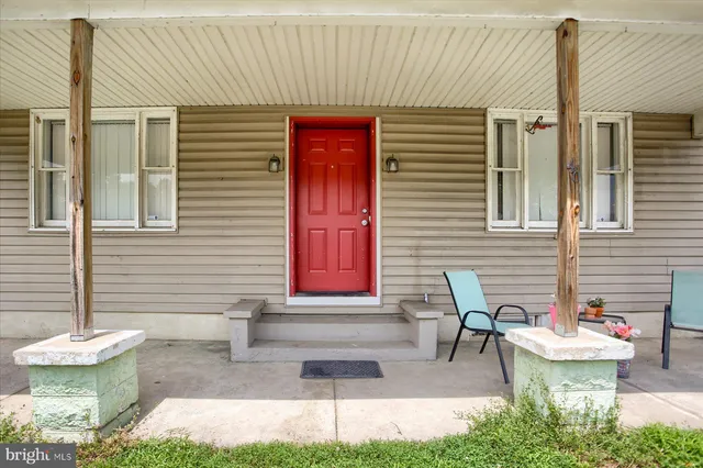 a front view of a house with porch and chairs