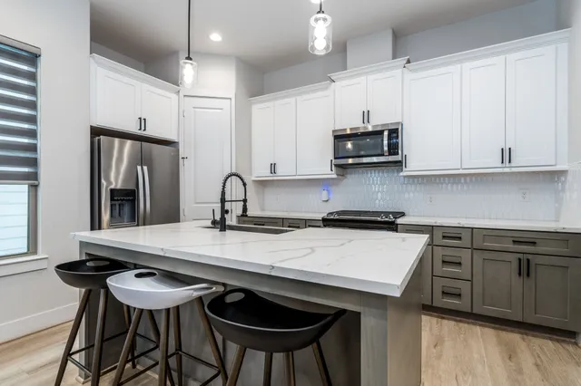 a kitchen with stainless steel appliances kitchen island granite countertop a dining table chairs and a refrigerator