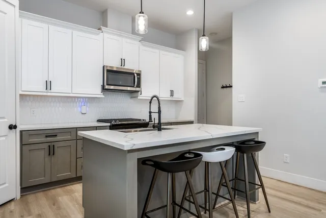 a kitchen with stainless steel appliances a table chairs in it and wooden floors