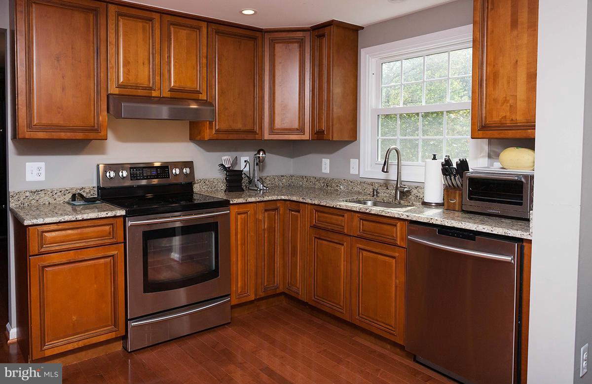 5750 Heming Avenue Springfield, VA 22151 - Photo 8 of 30 a kitchen with granite countertop wooden cabinets stainless steel appliances a sink and window