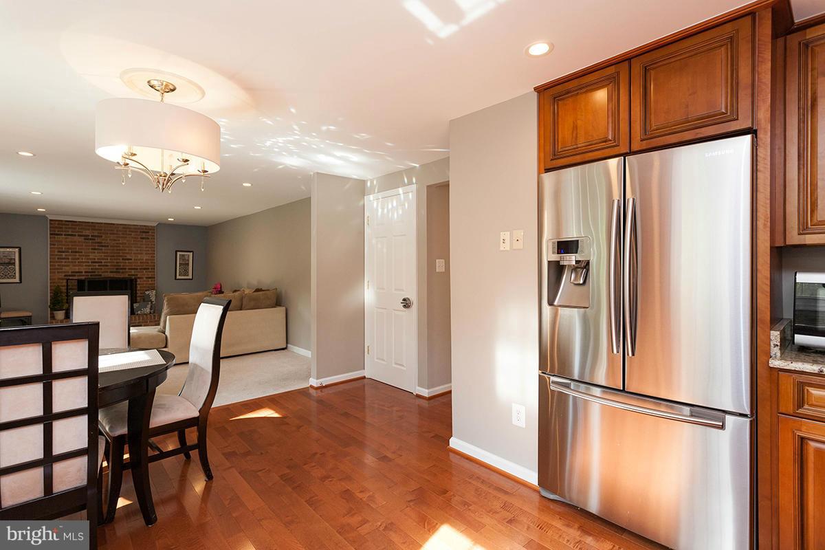 5750 Heming Avenue Springfield, VA 22151 - Photo 9 of 30 a kitchen with stainless steel appliances granite countertop a refrigerator a dining table and chairs with wooden floor