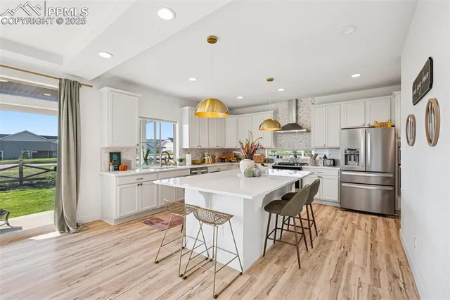 a kitchen with stainless steel appliances a refrigerator a stove a sink dishwasher and white cabinets with wooden floor