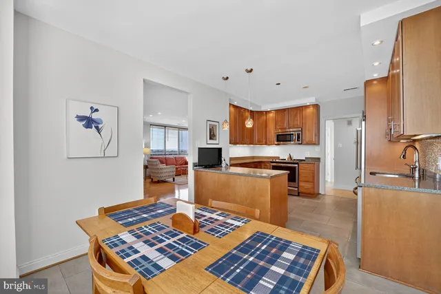 a living room with stainless steel appliances furniture a rug and a kitchen view
