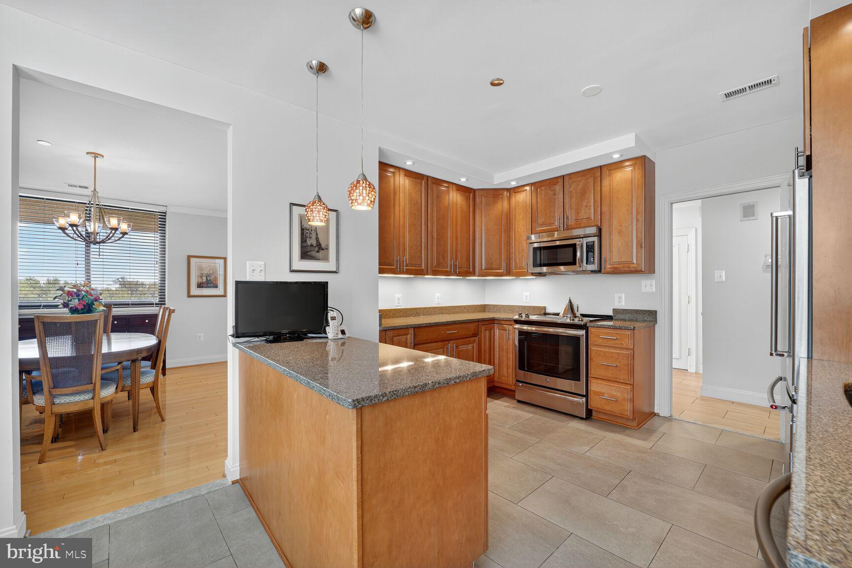 4550 North Park Avenue, Unit 1005 Chevy Chase, MD 20815 - Photo 14 of 30 a kitchen with stainless steel appliances granite countertop a stove top oven a sink dishwasher a dining table and chairs with wooden floor