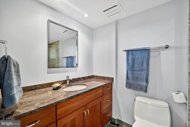 a bathroom with a granite countertop sink toilet and shower
