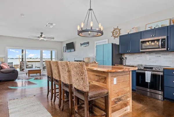 a kitchen with stainless steel appliances granite countertop a stove a refrigerator a oven a sink a dining table and chairs with wooden floor