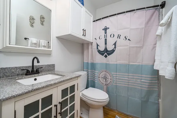 a bathroom with a granite countertop sink a toilet and a shower curtain