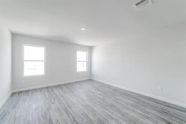 a view of an empty room with wooden floor and closet