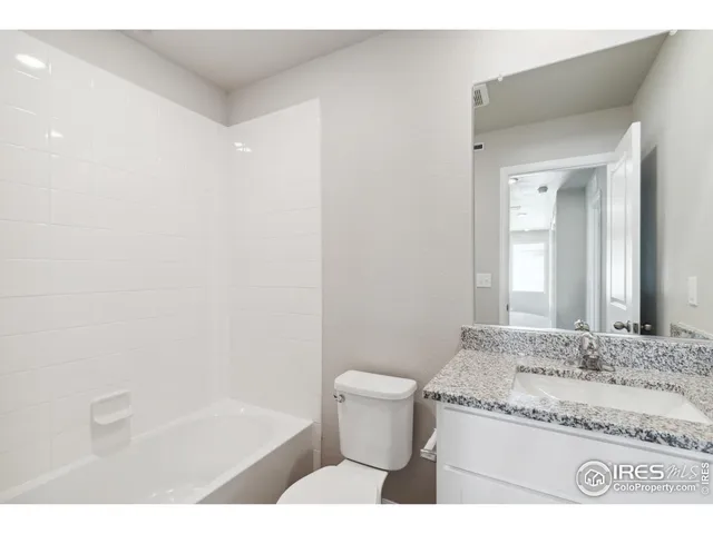 a bathroom with a granite countertop sink a toilet and bathtub
