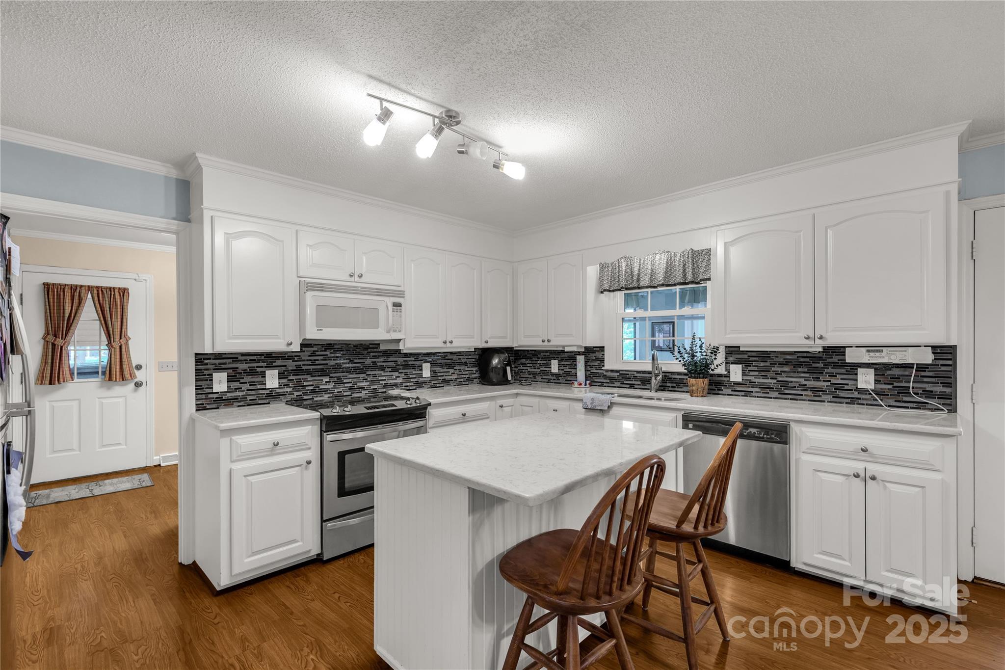 1162 East Doc Garris Road Lancaster, SC 29720 - Photo 11 of 31 a kitchen with a stove a sink a kitchen island and chairs in it