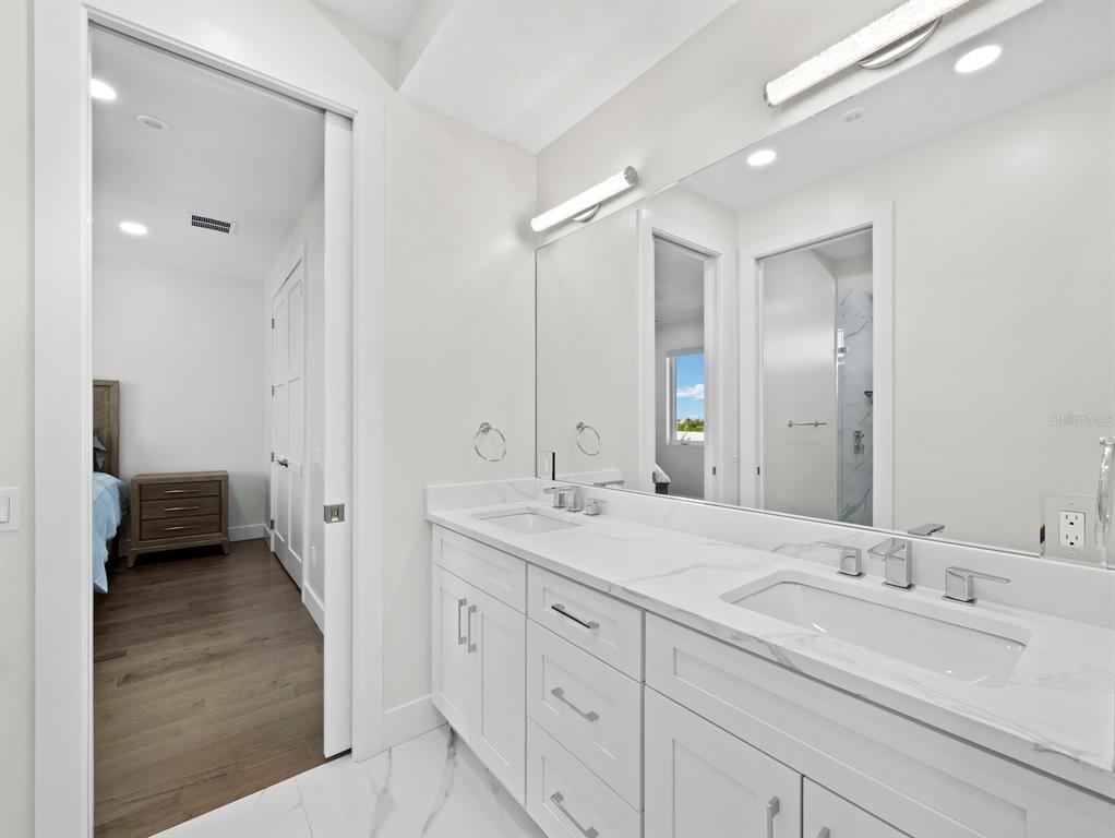 635 Jungle Queen Way Longboat Key, FL 34228 - Photo 35 of 55 a en suite bathroom with a double vanity sink and mirror