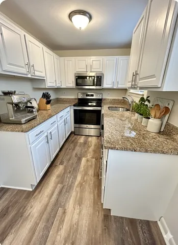 a kitchen with granite countertop a sink a stove top oven and cabinetry