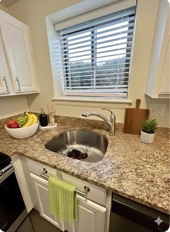 a kitchen with a granite countertop sink stove and cabinets