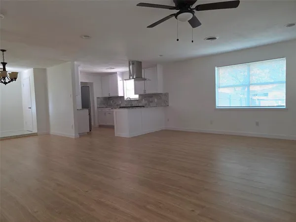 a large kitchen with a wooden floor and white cabinets