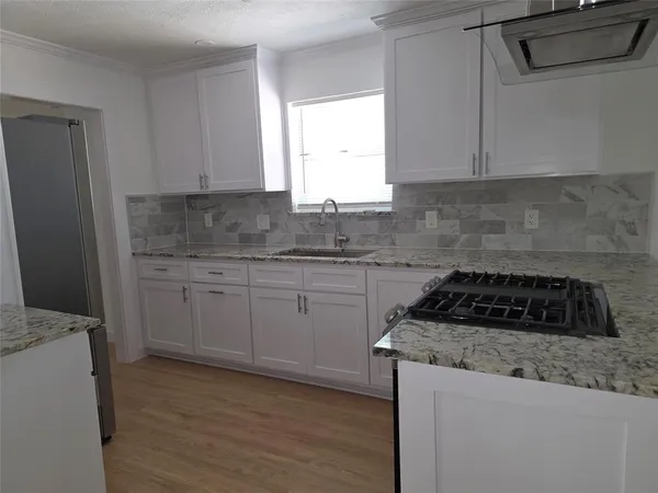 a kitchen with granite countertop a sink a stove and cabinets