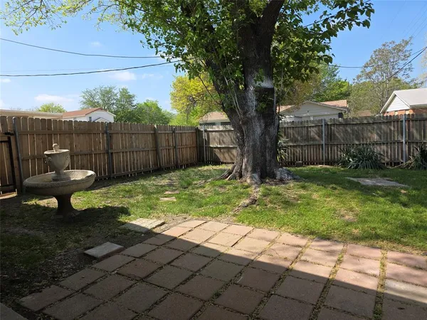 a view of a backyard with large trees and wooden fence