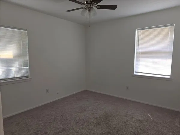 an empty room with a window and a fan