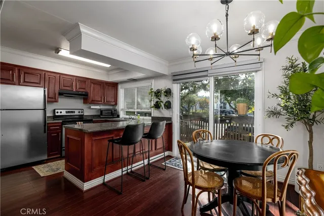 a kitchen with granite countertop a table chairs stove and refrigerator