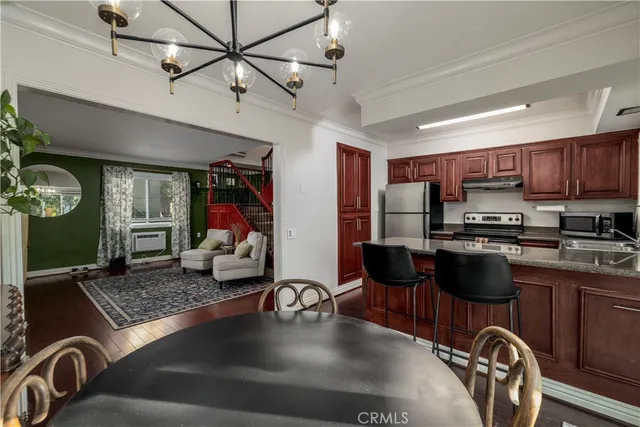 a kitchen with stainless steel appliances granite countertop a sink dishwasher a stove a refrigerator with a dining table and chairs