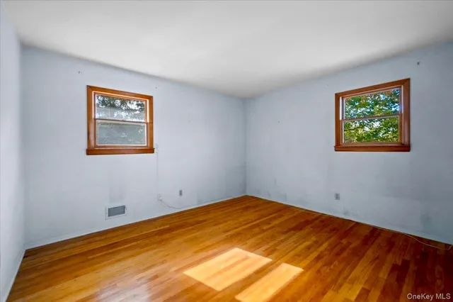 a view of empty room with window and wooden floor