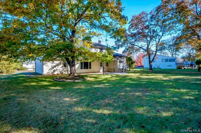 a view of a white house with a small yard and large tree