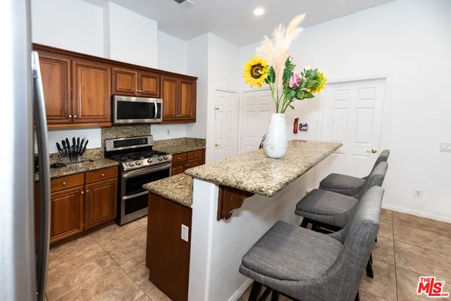 a kitchen with granite countertop kitchen island stainless steel appliances a stove refrigerator sink and a microwave