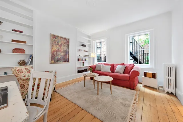 a living room with furniture a wooden floor and next to a window