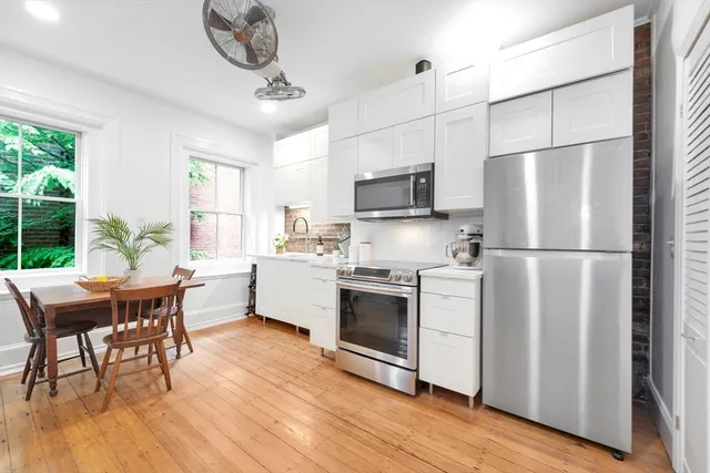 a kitchen with stainless steel appliances granite countertop a refrigerator a stove a sink dishwasher a microwave oven with a dining table and chairs with wooden floor