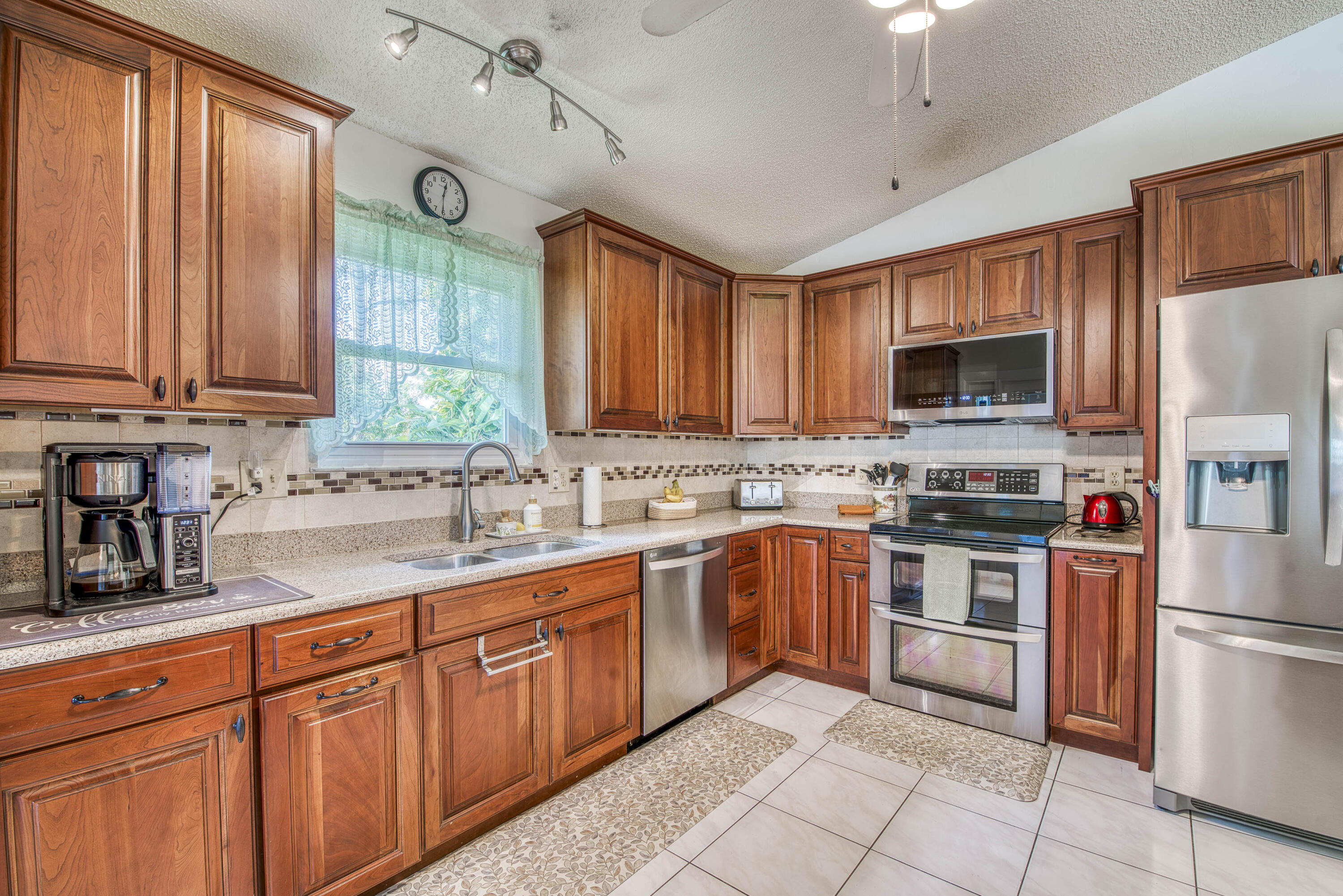 6690 Southeast Raintree Avenue Stuart, FL 34997 - Photo 15 of 43 a kitchen with stainless steel appliances granite countertop a stove top oven a sink dishwasher a refrigerator and a microwave oven