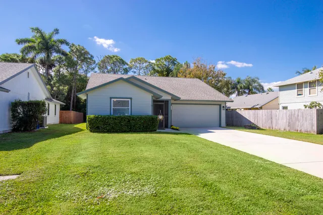 a yellow house with a yard and a large tree