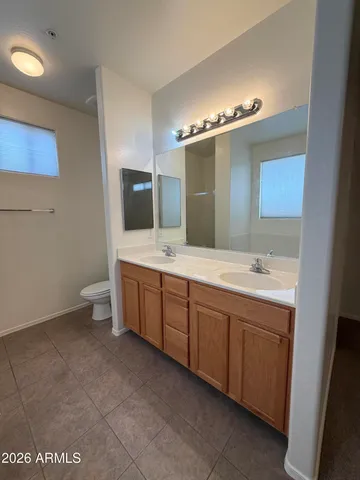a spacious bathroom with a double vanity sink a toilet and mirror