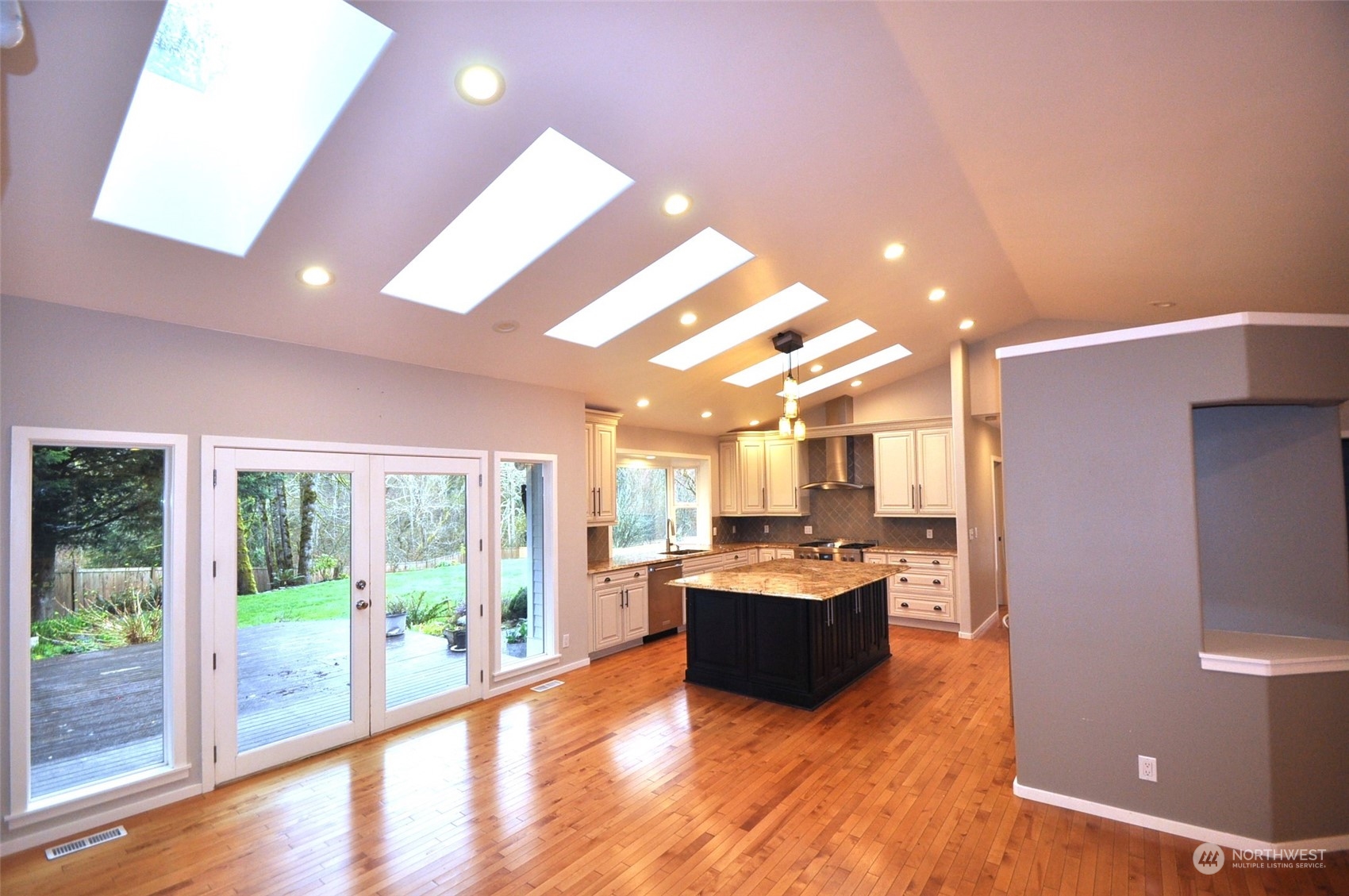 13003 Lake Kathleen Road Southeast Renton, WA 98059 - Photo 3 of 13 a living room with stainless steel appliances kitchen island granite countertop a refrigerator a stove top oven and a large window with wooden floor