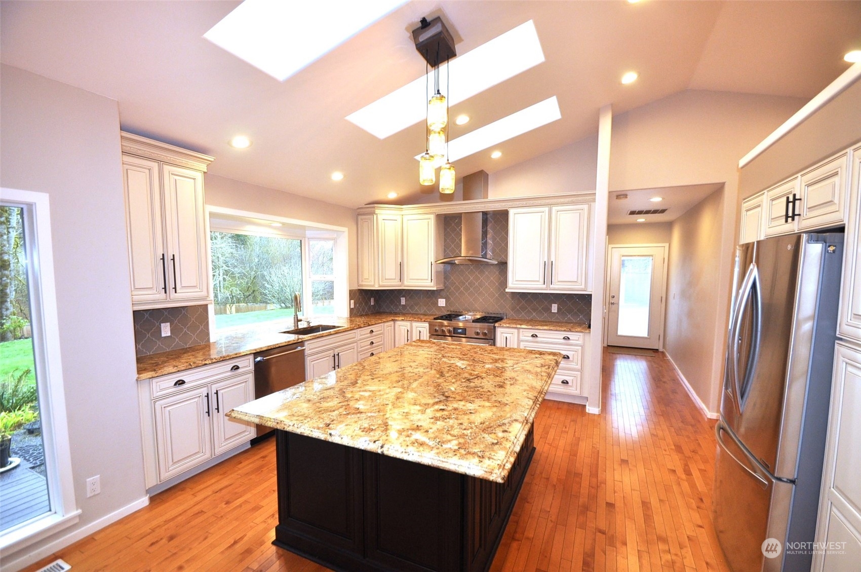 13003 Lake Kathleen Road Southeast Renton, WA 98059 - Photo 4 of 13 a kitchen with kitchen island a large counter top space a sink stainless steel appliances and cabinets