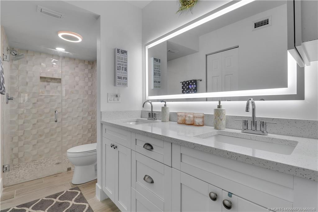 1001 Keystone Drive, Unit A Jupiter, FL 33458 - Photo 20 of 30 a bathroom with a double vanity sink toilet and a mirror