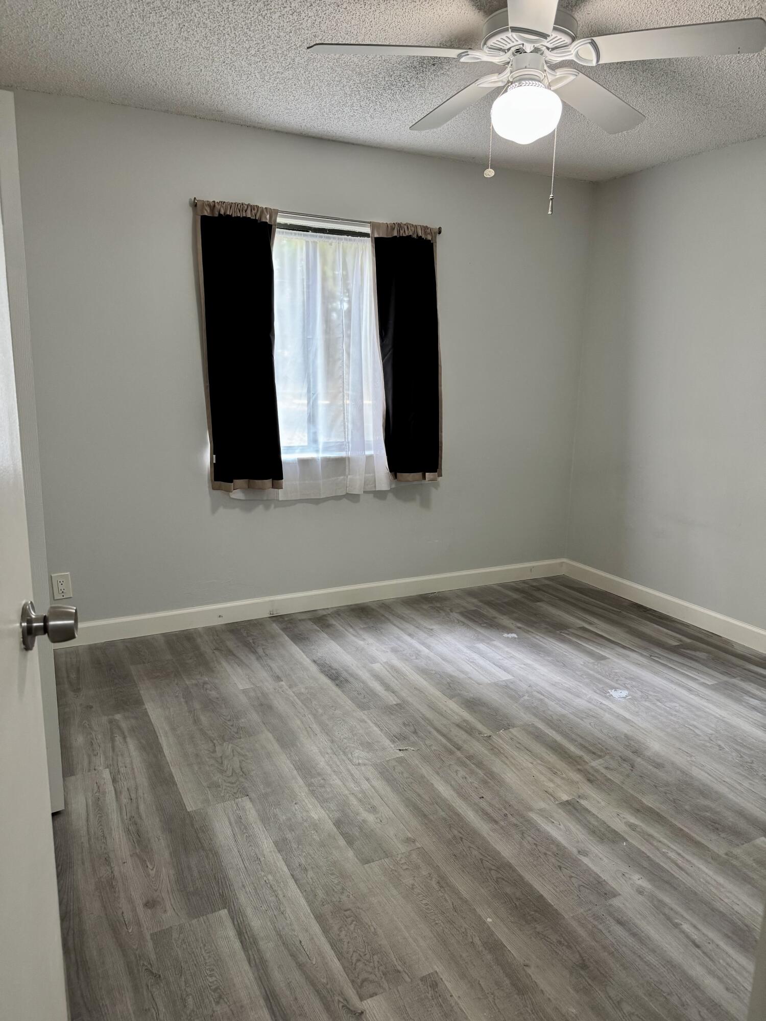 912 Southwest 9th St Circle, Unit 101 Boca Raton, FL 33486 - Photo 20 of 25 a view of an empty room with wooden floor and fan