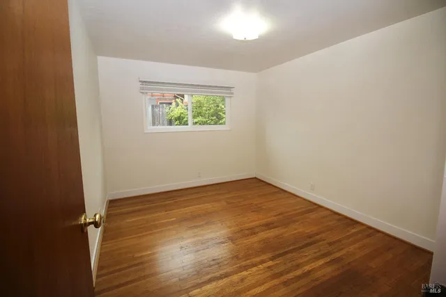 an empty room with wooden floor and window