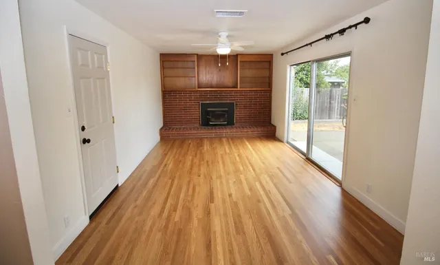 a view of empty room with wooden floor and fireplace