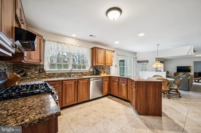 a kitchen with stainless steel appliances granite countertop a stove top oven a sink a dining table and chairs