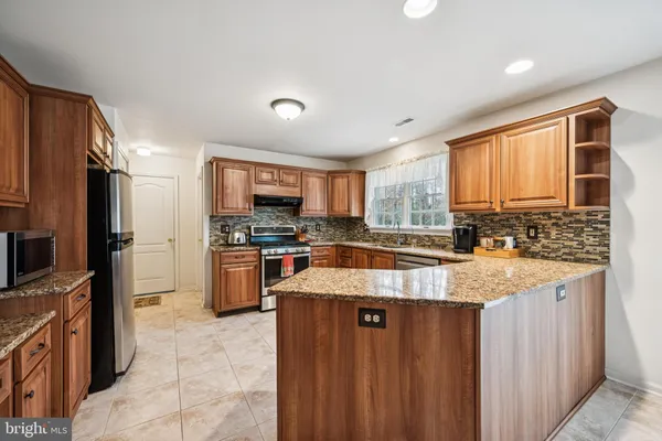 a large kitchen with granite countertop a large counter top stainless steel appliances and cabinets