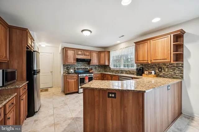 a large kitchen with granite countertop a large counter top stainless steel appliances and cabinets