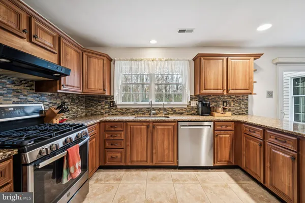 a kitchen with stainless steel appliances granite countertop a stove a sink dishwasher and a microwave oven with cabinets