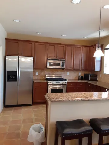 a kitchen with stainless steel appliances granite countertop a table chairs microwave and refrigerator