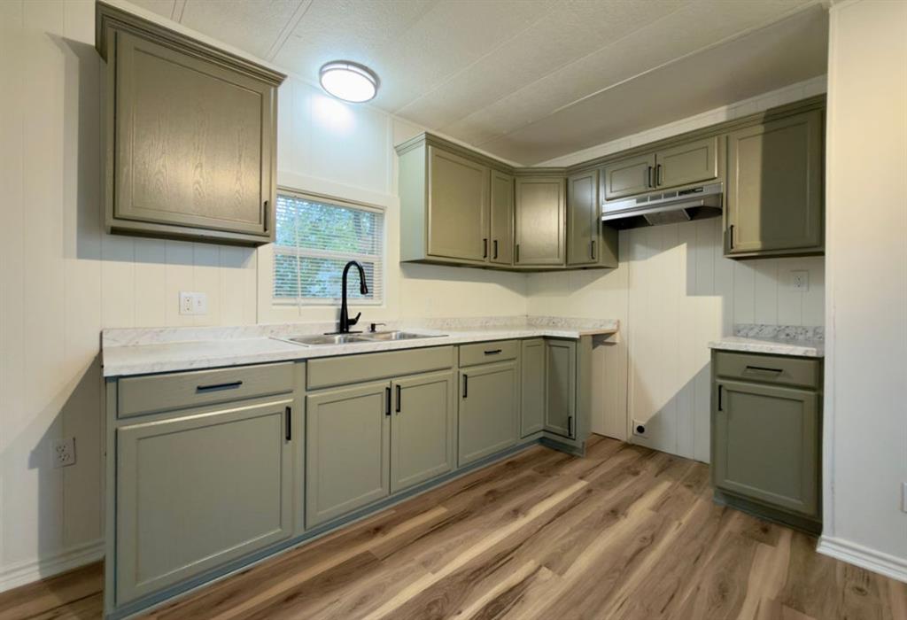 305 West Bryant Street Elm Mott, TX 76640 - Photo 4 of 19 Kitchen featuring light wood-type flooring, light countertops, under cabinet range hood, and gray cabinets