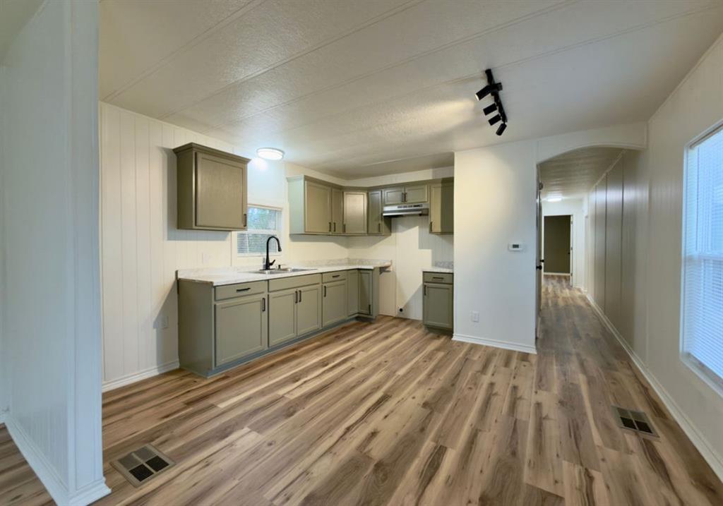305 West Bryant Street Elm Mott, TX 76640 - Photo 5 of 19 Kitchen featuring light countertops, dark wood-style floors, gray cabinetry, track lighting, and arched walkways