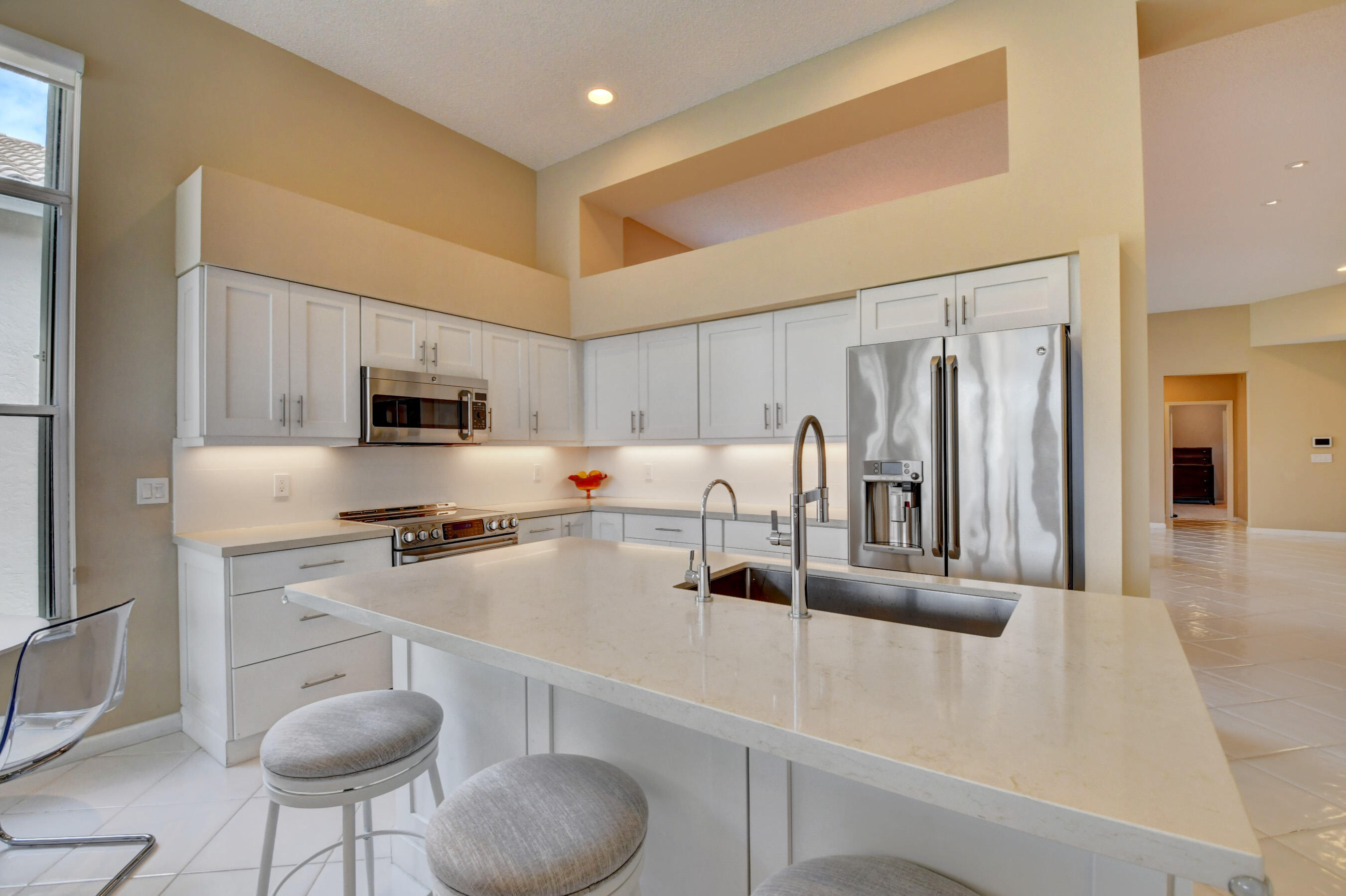 2331 Northwest 66th Drive Boca Raton, FL 33496 - Photo 17 of 71 a kitchen with stainless steel appliances a sink a stove a refrigerator cabinets and chairs