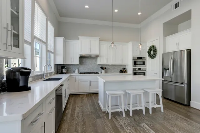 a kitchen with stainless steel appliances granite countertop a stove a sink a refrigerator and white cabinets