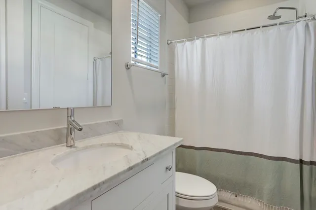 a bathroom with a granite countertop sink toilet and a mirror