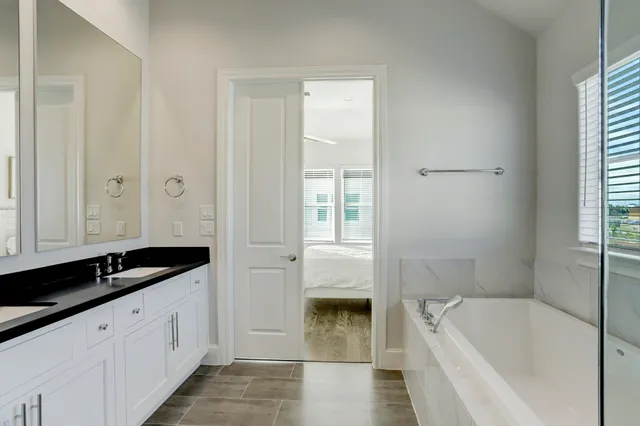 a spacious bathroom with a granite countertop tub a sink and a mirror