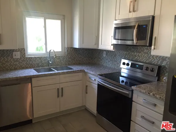 a kitchen with granite countertop a sink stove and microwave