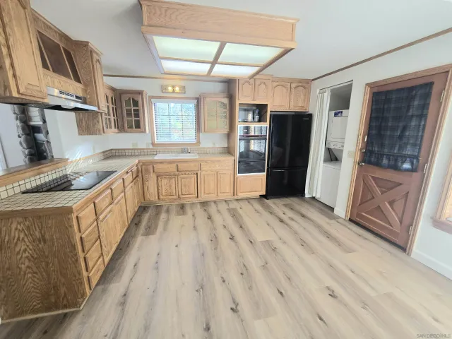 a kitchen with stainless steel appliances granite countertop a refrigerator a sink dishwasher a stove and white countertops with wooden floor